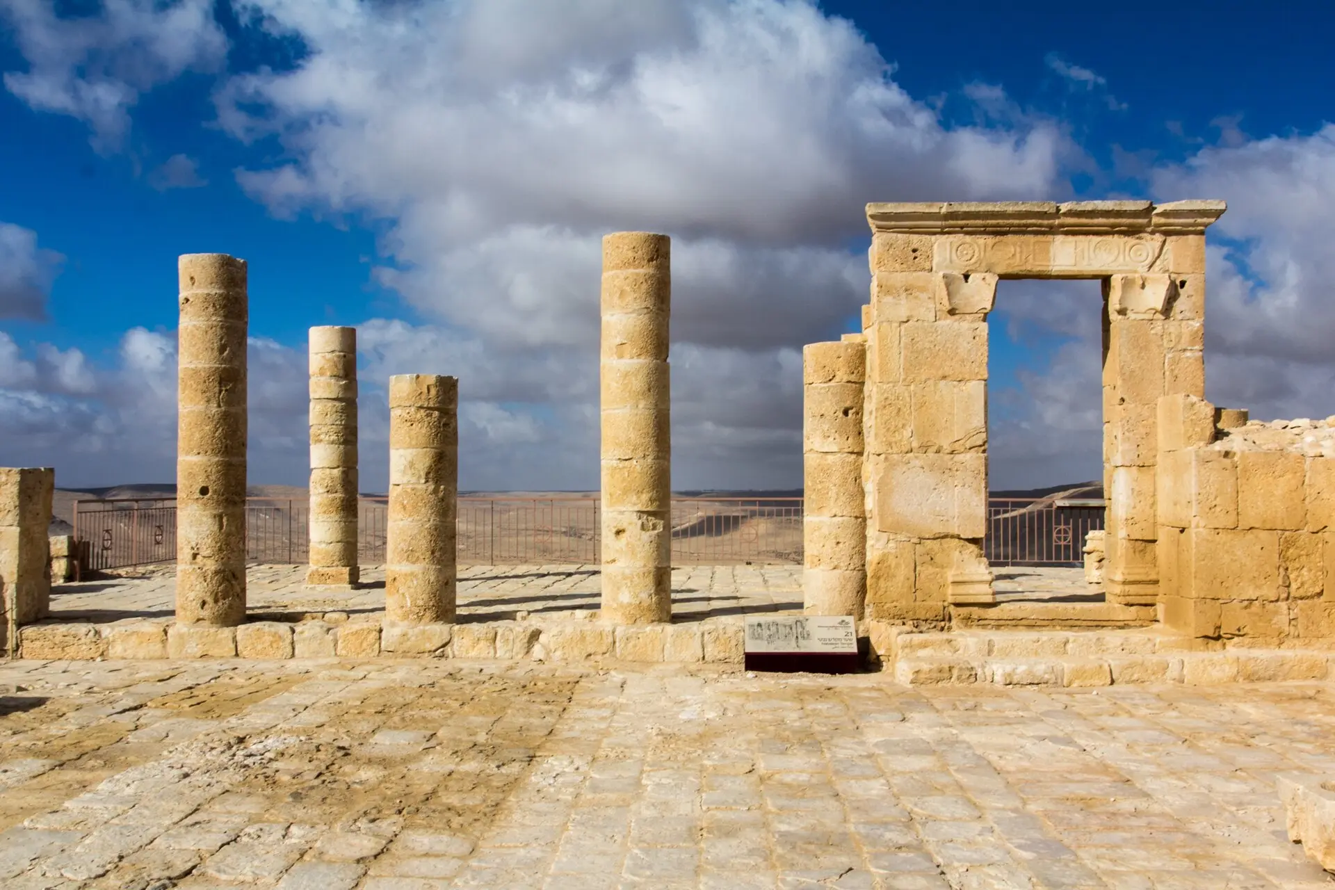 עמודים ושער אבן על האקרופוליס של עבדת, מתחת לשמיים עם עננים