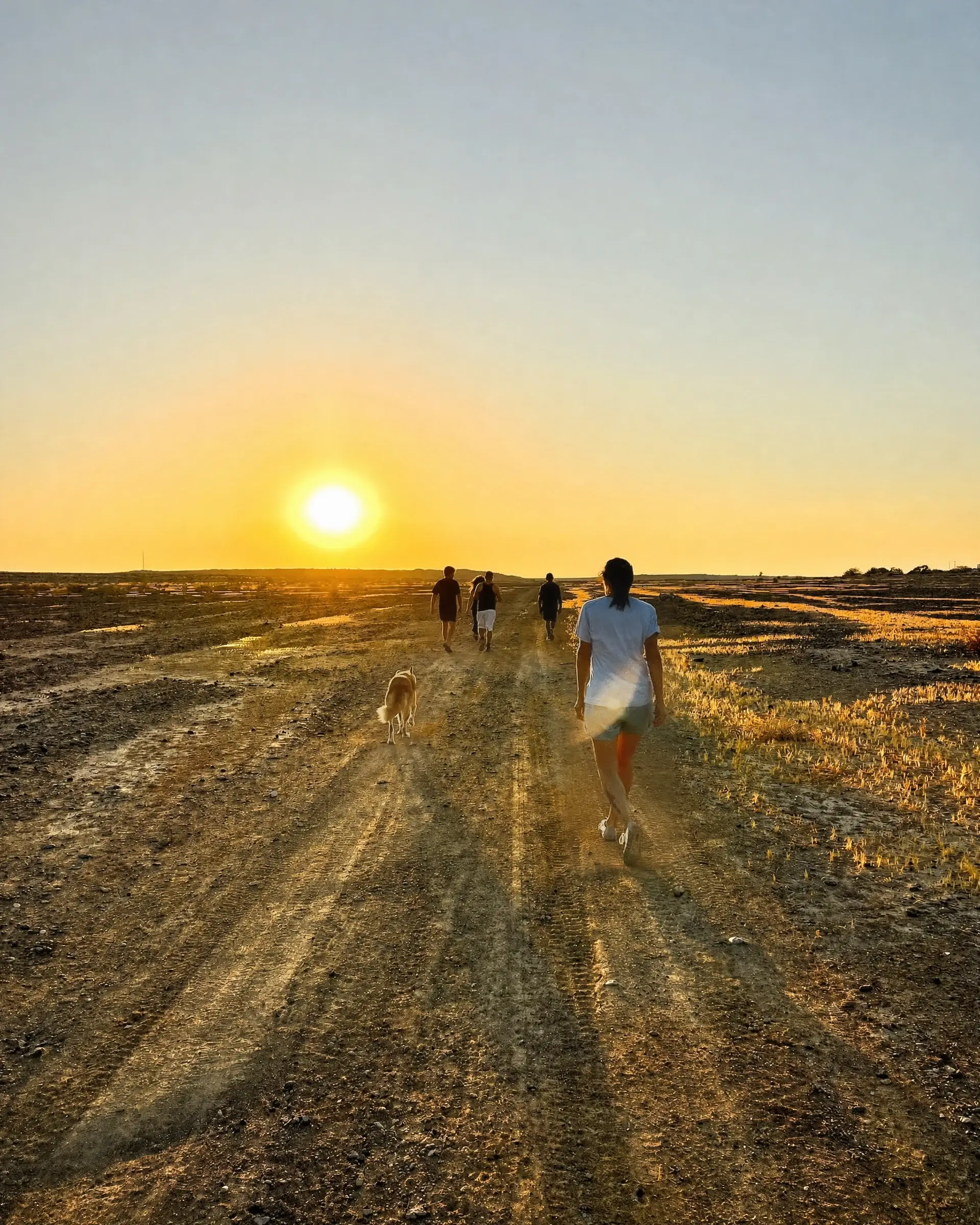 Walking down a dirt road toward the sunset