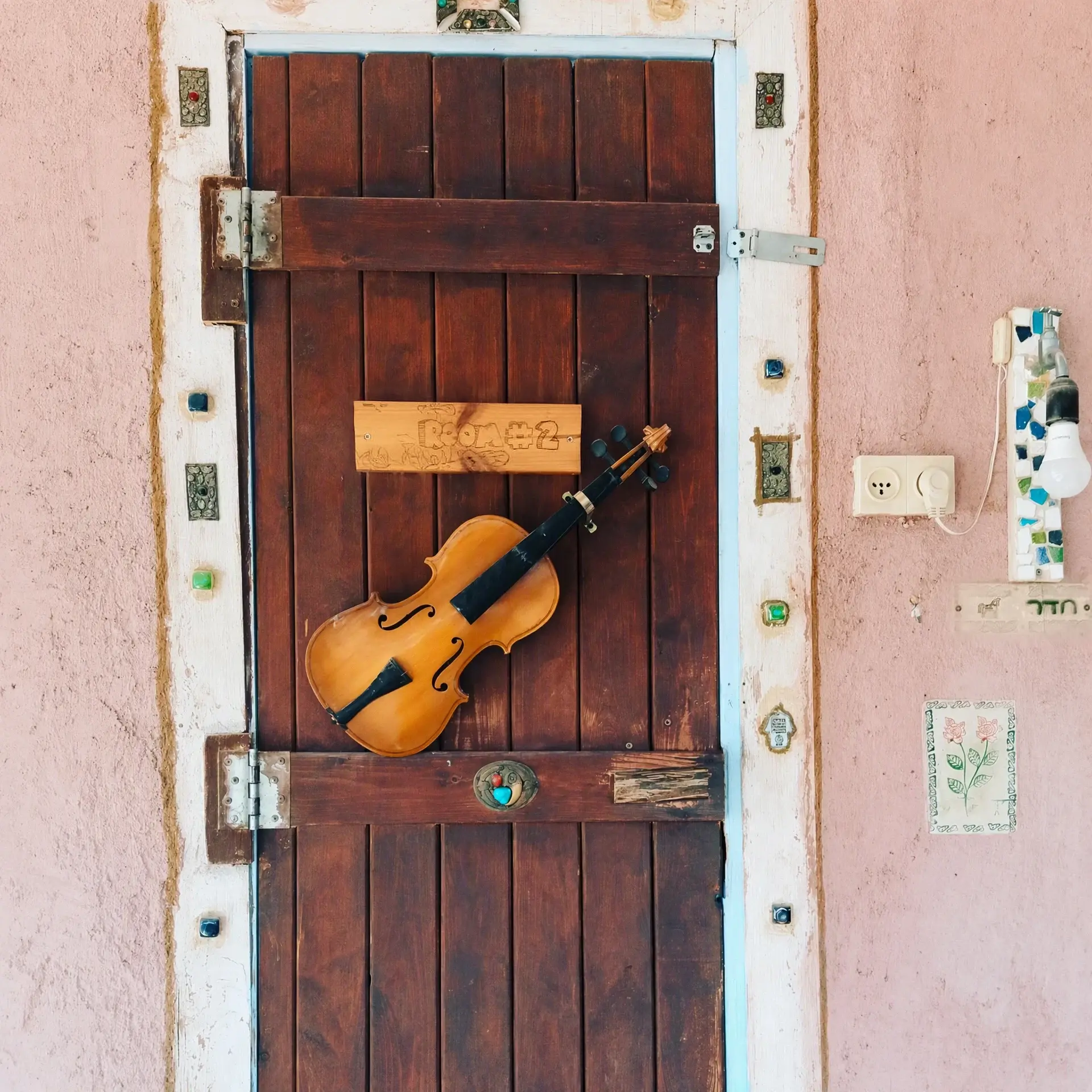 A red wooden door with a violin hung on it