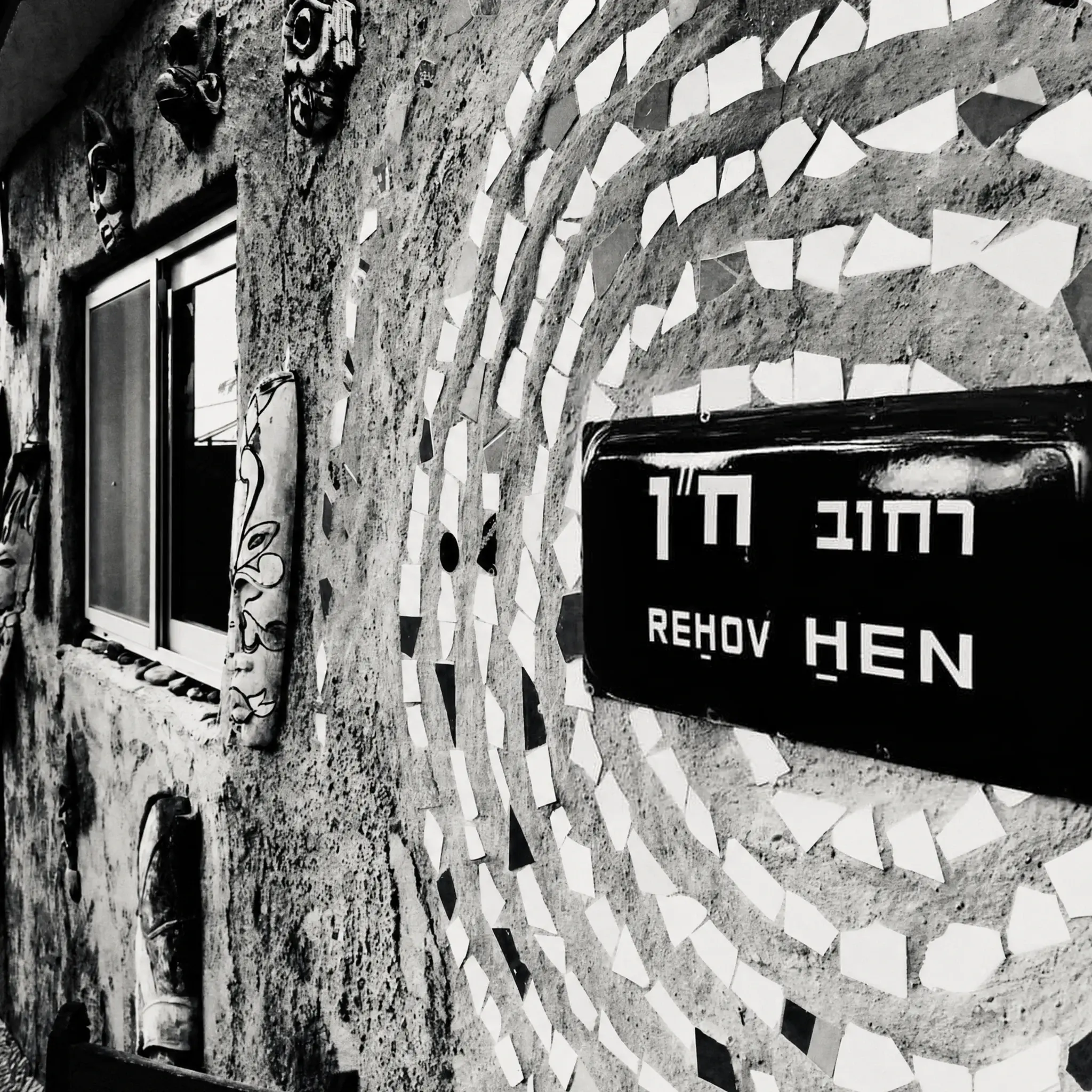 The “Rehov Hen” street sign on a mosaic wall, in black and white