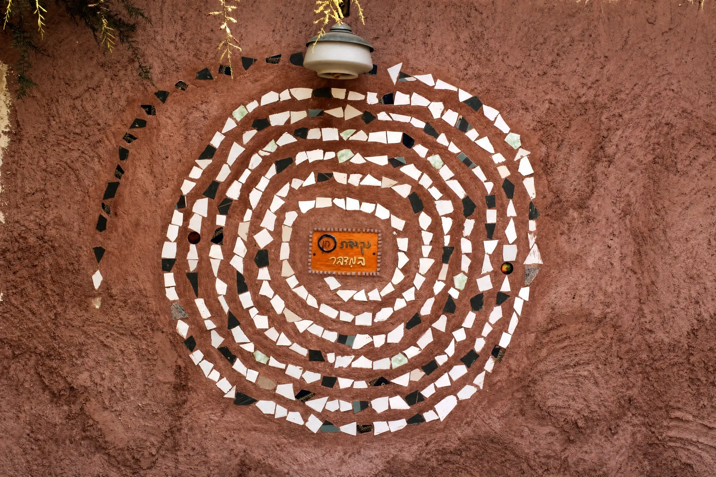 A white mosaic spiral on a terracotta wall