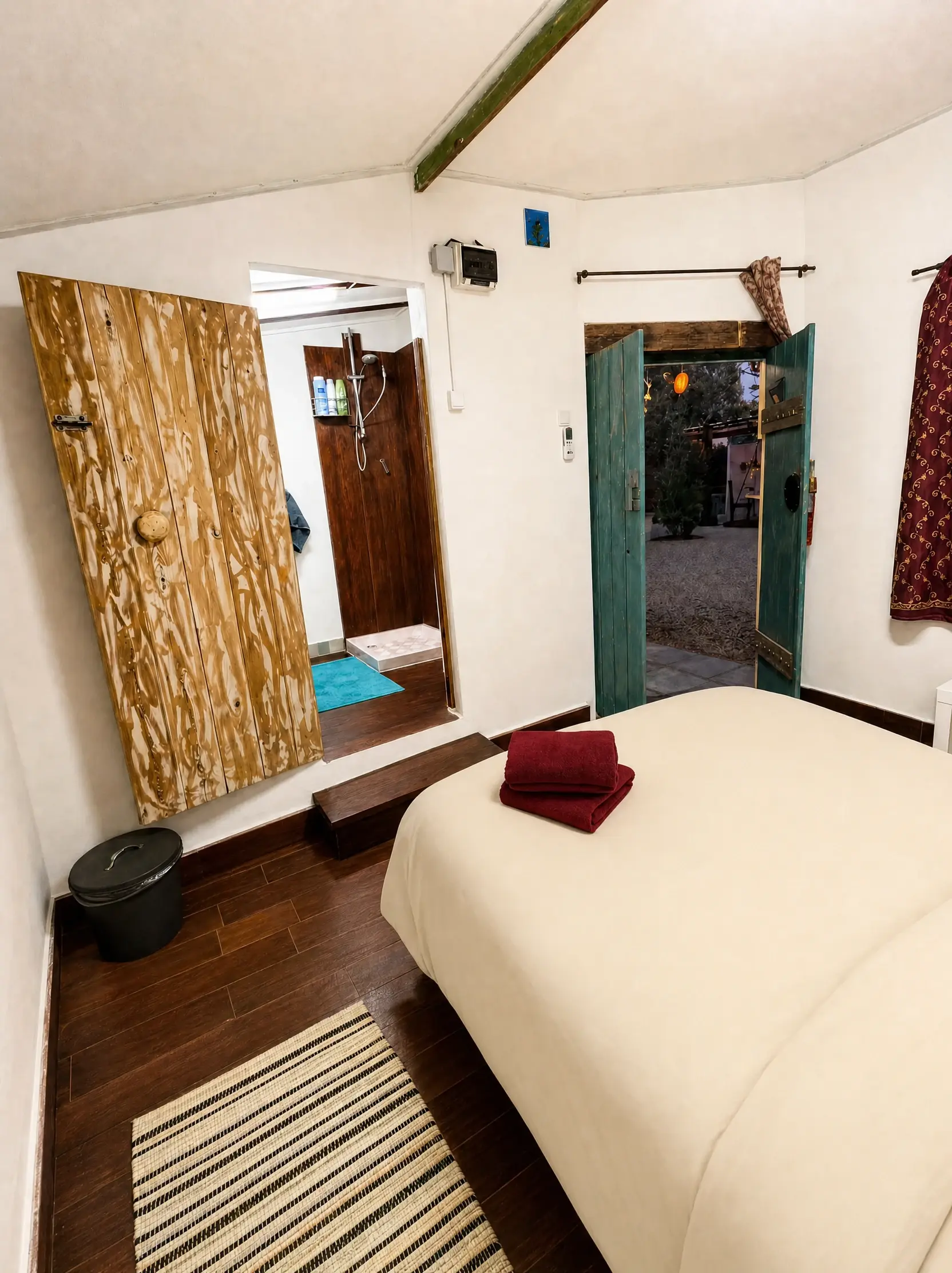 The Eden room at night: the double bed, a wooden door to the bathroom and doors open to the yard