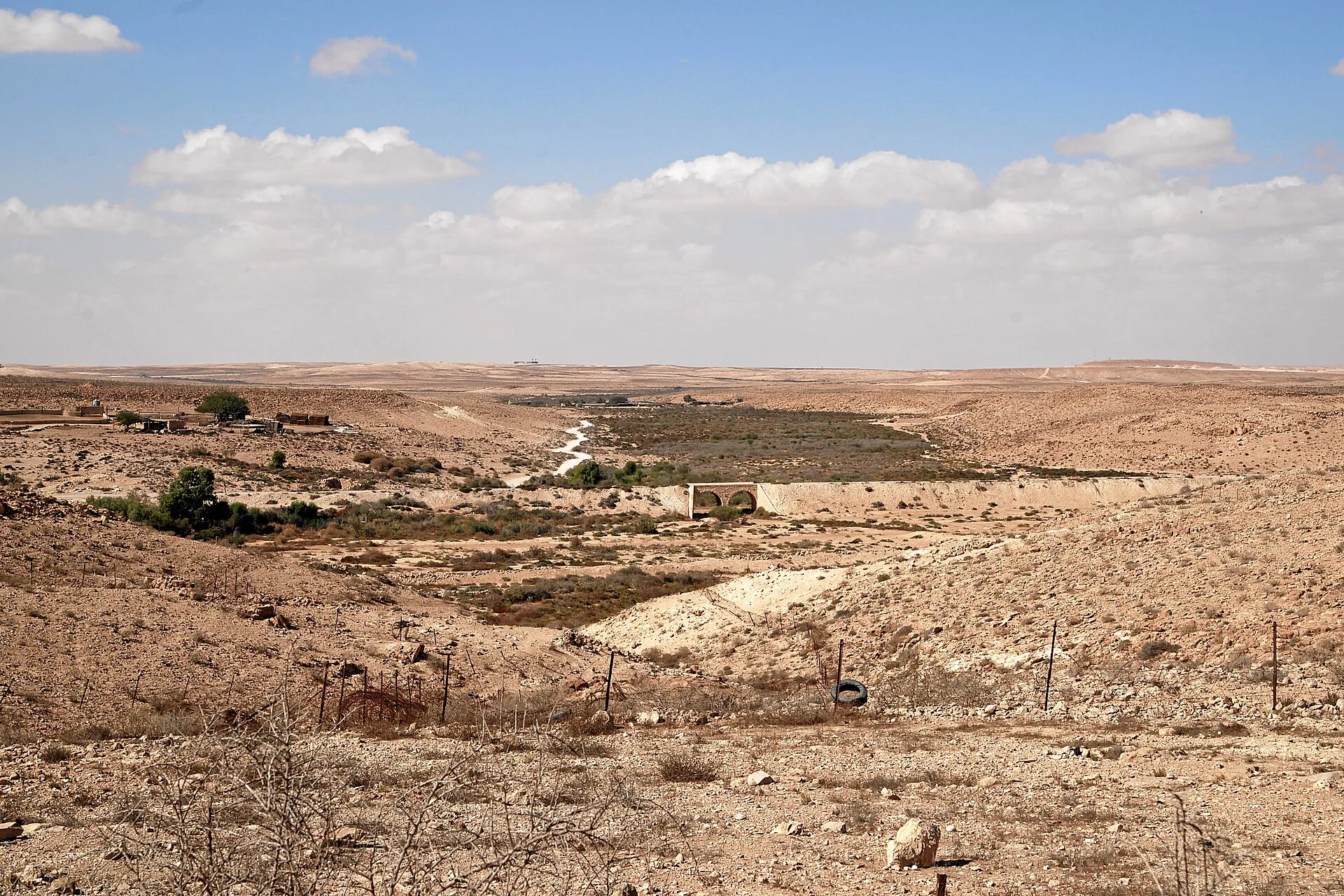 ערוץ נחל רחב ליד עזוז, ובו צמחייה ירוקה וגשר הרכבת הטורקי בעל שתי הקשתות