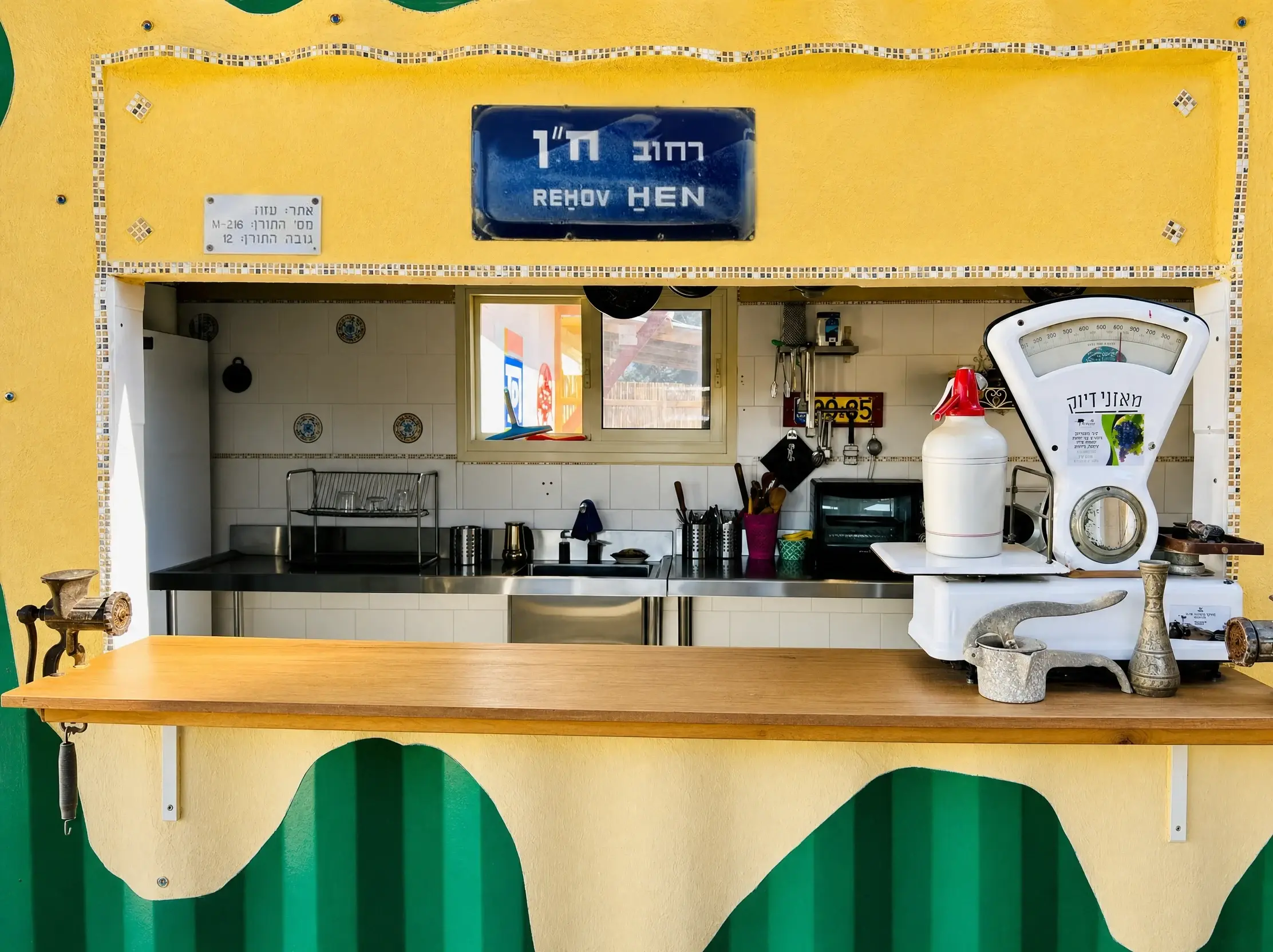The shared kitchen hatch, with a “Rehov Hen” street sign and an antique scale