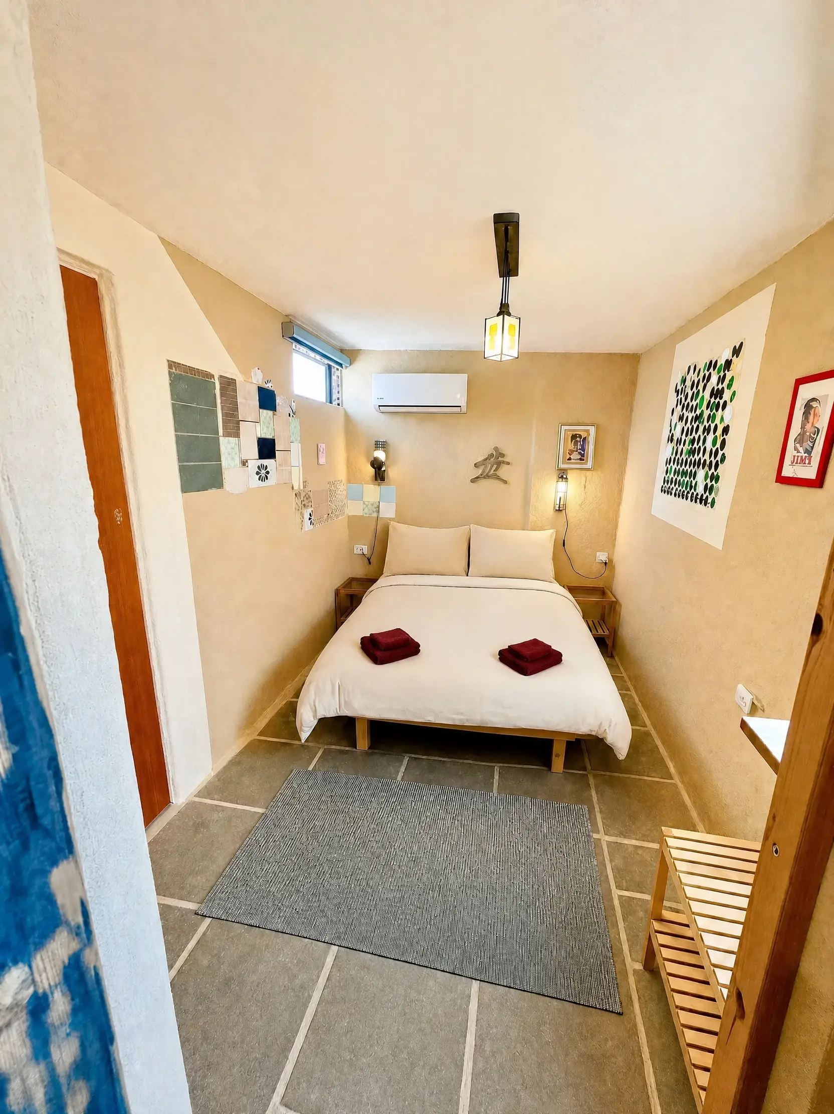 The Maayan room from the doorway: the bed, a wooden bench and a rug
