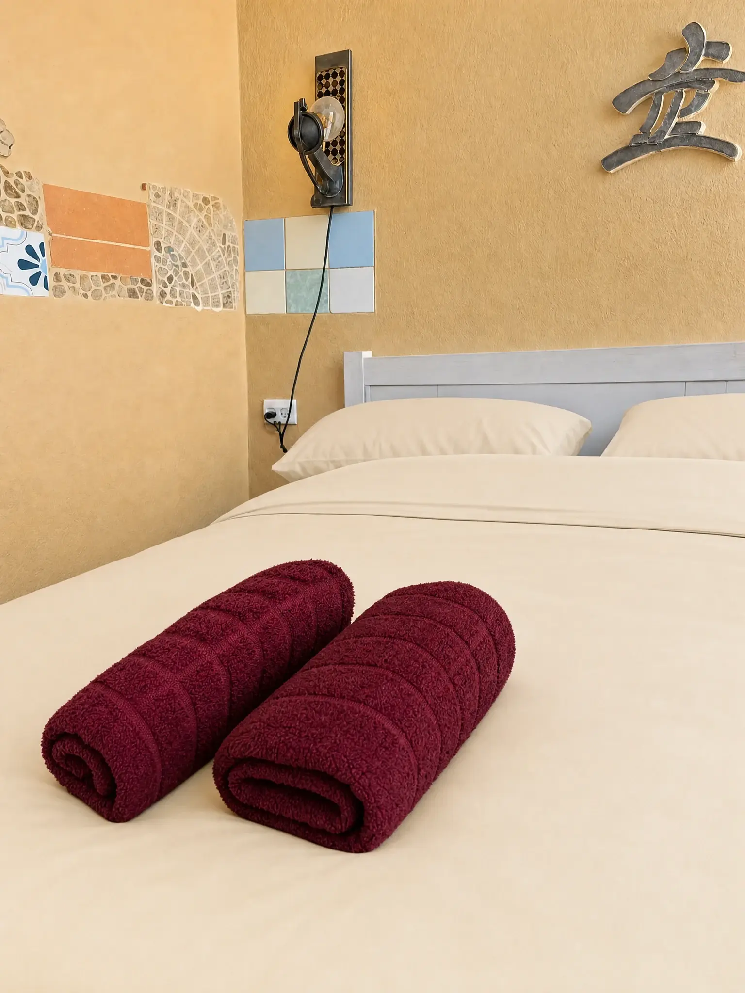 The Maayan bed with light beige linens and towels