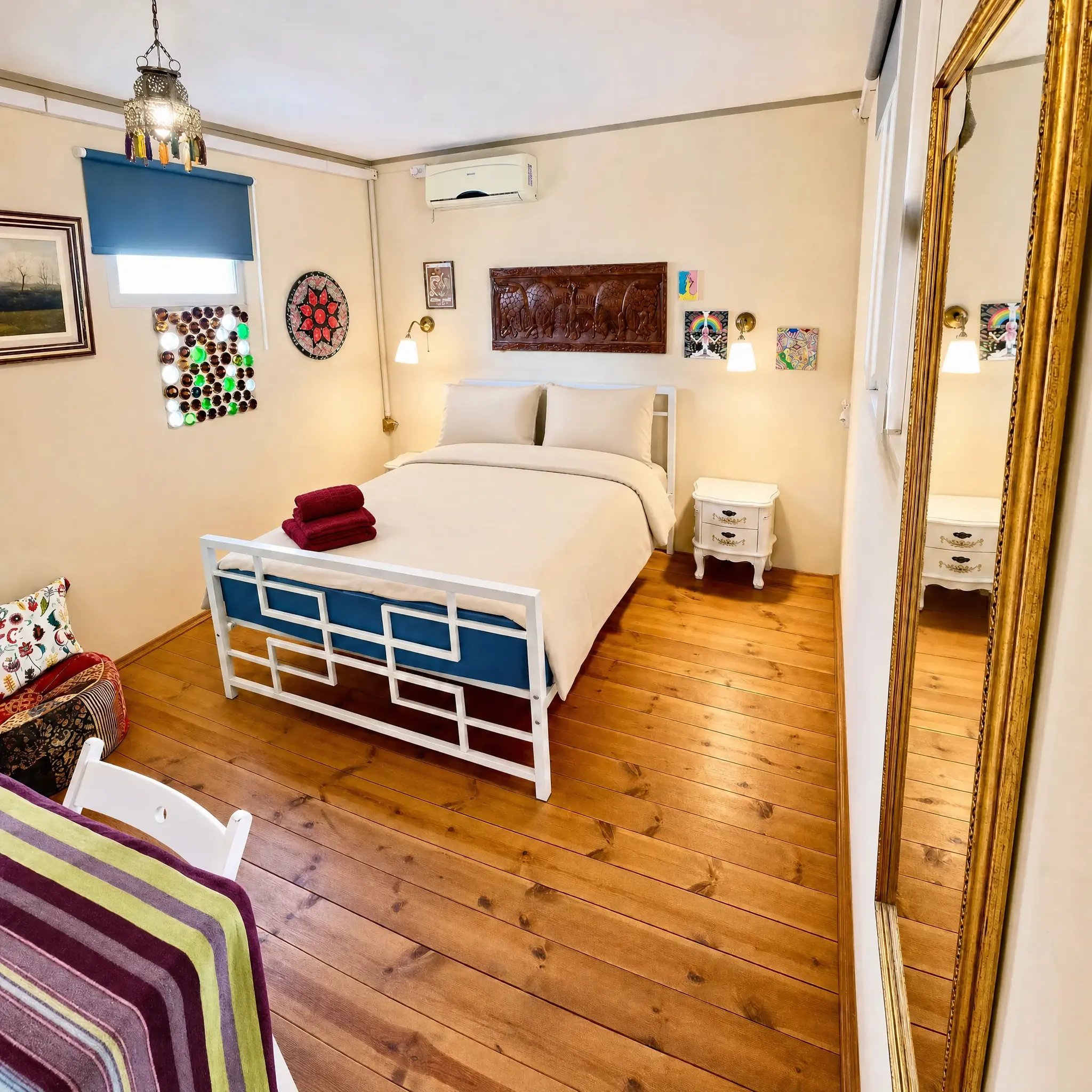 The Muse room: a double bed, a colorful bottle window and a mandala plate on the wall