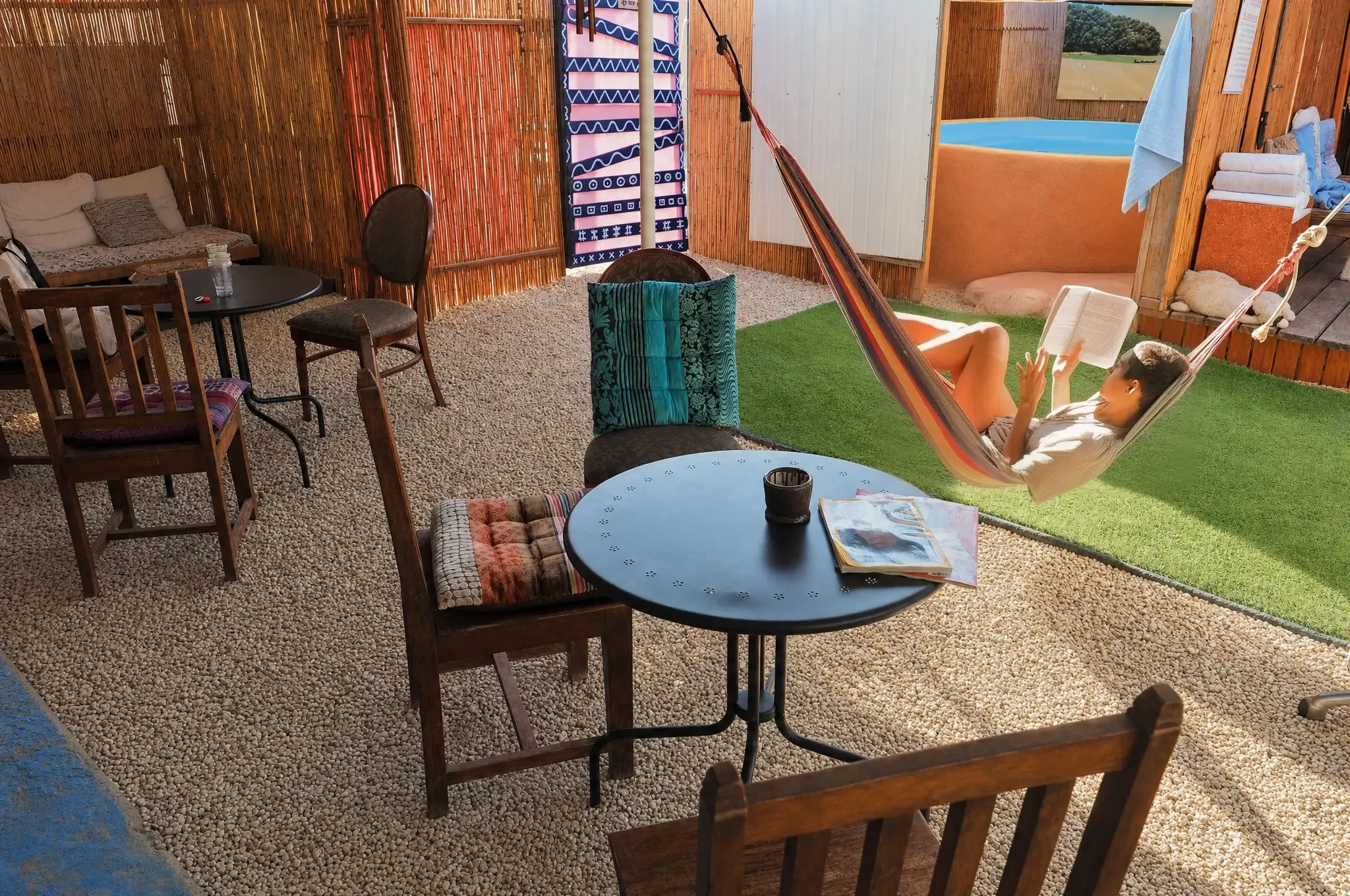 The garden facing Muse: a hammock, wooden chairs and small tables