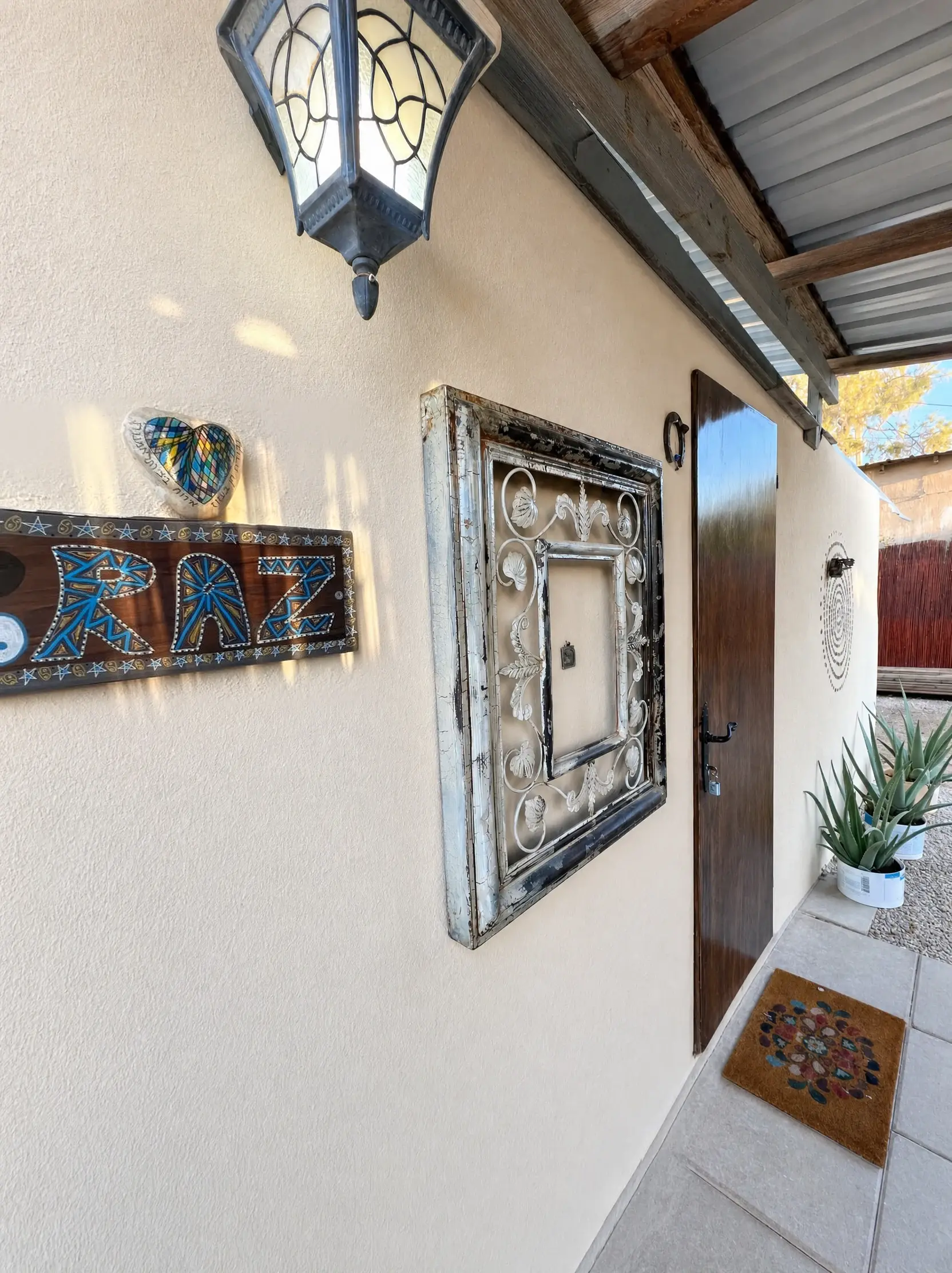 The Raz entrance: a painted wooden sign, a stained-glass lantern and an ornate iron frame