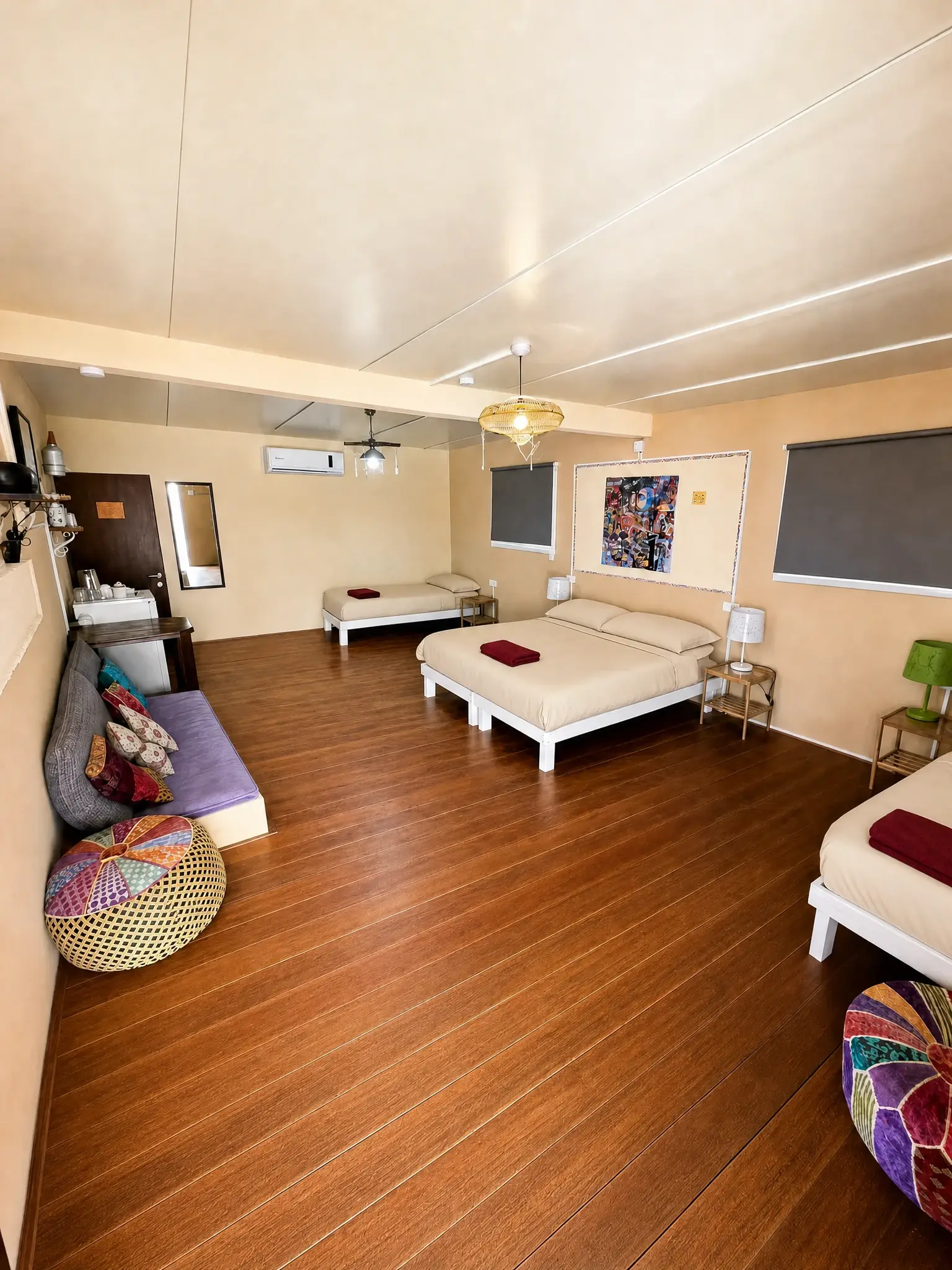 The Studio, wide view: beds, colorful poufs and a wooden floor