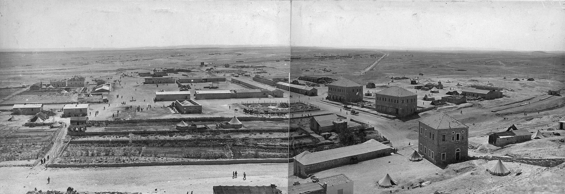 פנורמה בשחור־לבן של העיירה הצבאית העות׳מאנית בעוג׳ה אל־חפיר ב־1916: מבני אבן, אוהלים ומרחב מדברי