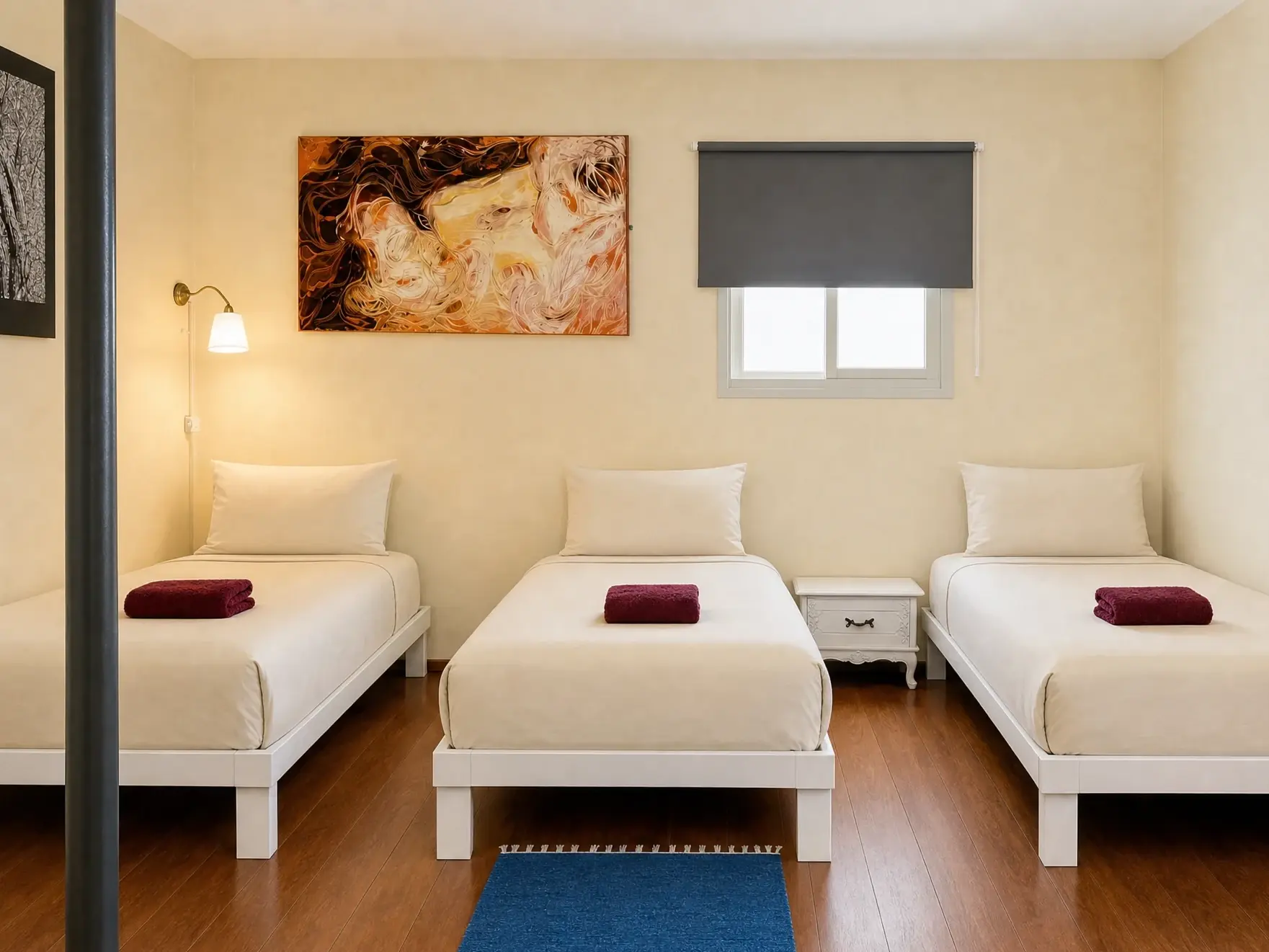The Triple room: three single beds, a blue rug and a painting on the wall