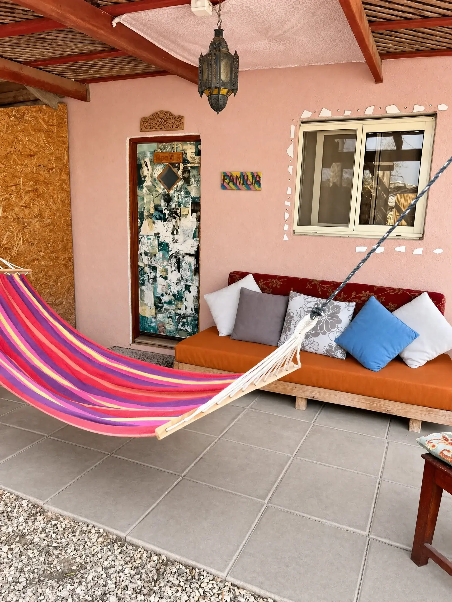 Outside the Triple room: a pink wall, a mosaic door, a sofa and a hammock