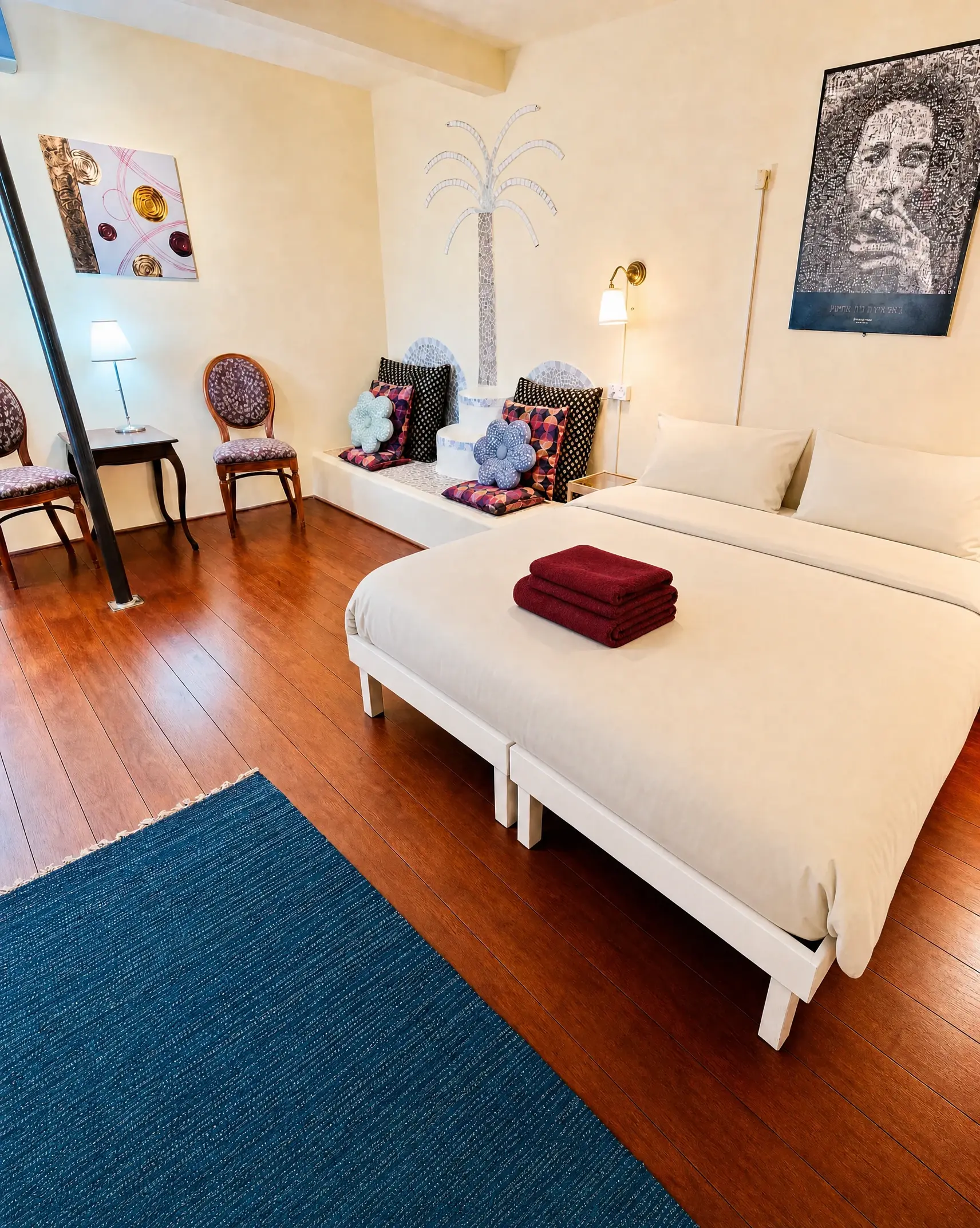 The Triple room: single beds with light beige linens, armchairs and a palm painted on the wall