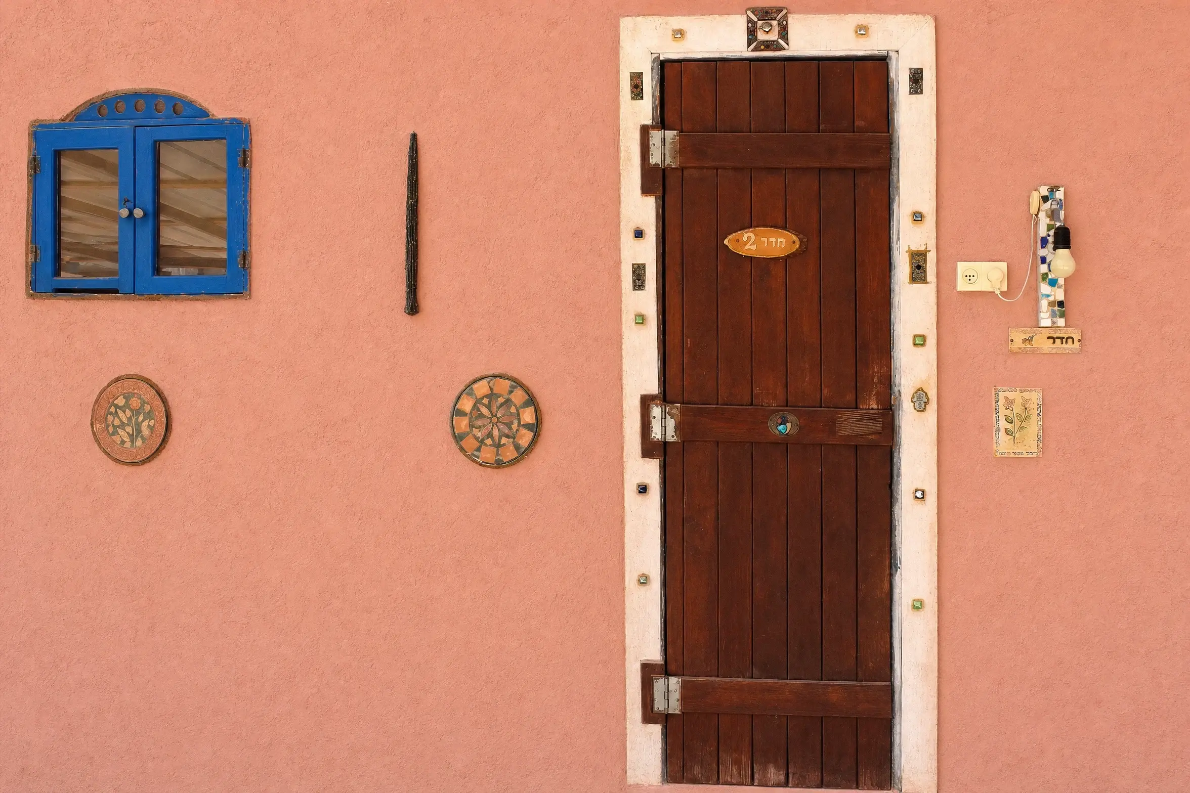 A pink wall and a wooden door at the Triple entrance