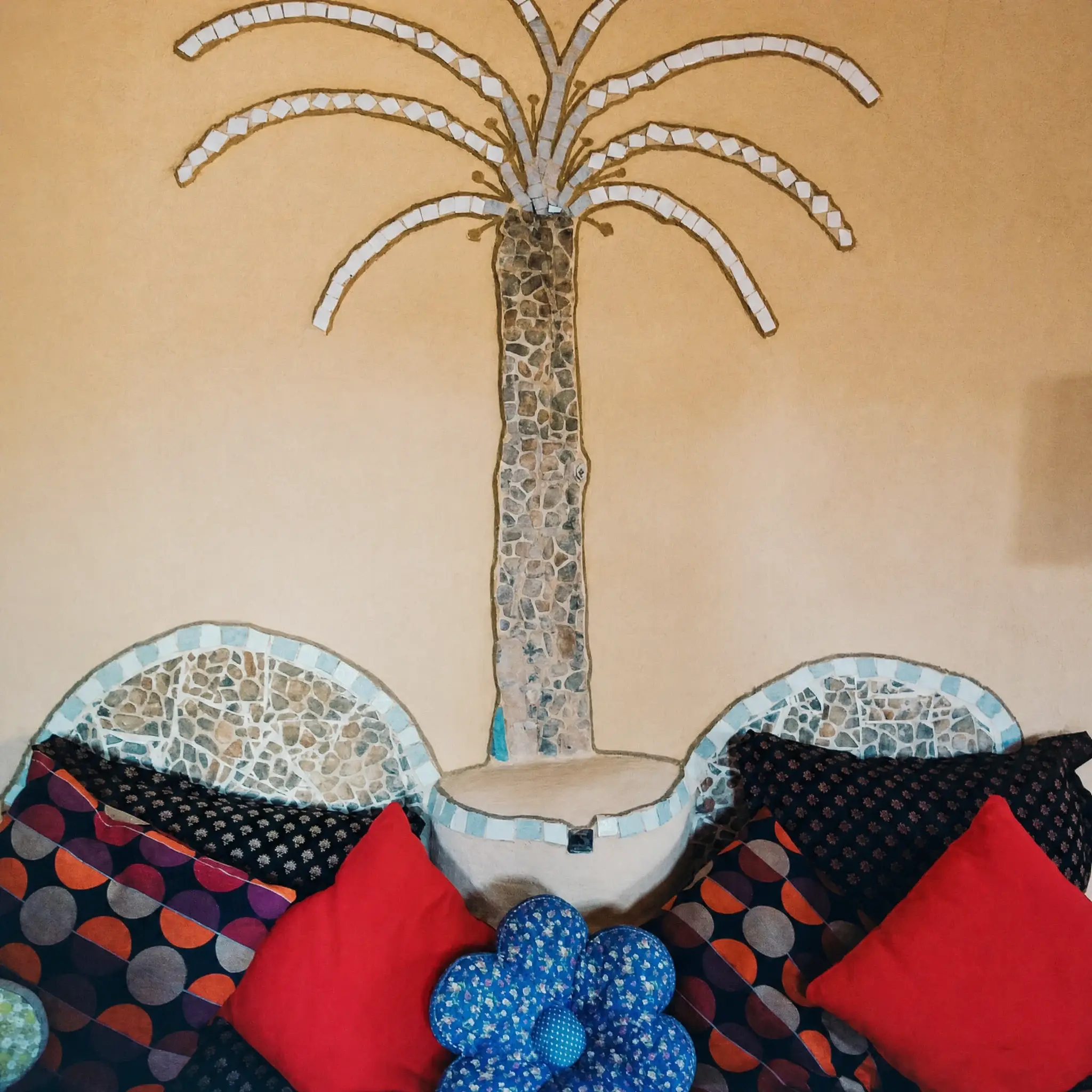 A mosaic palm on the Triple room wall, above a cushioned bench