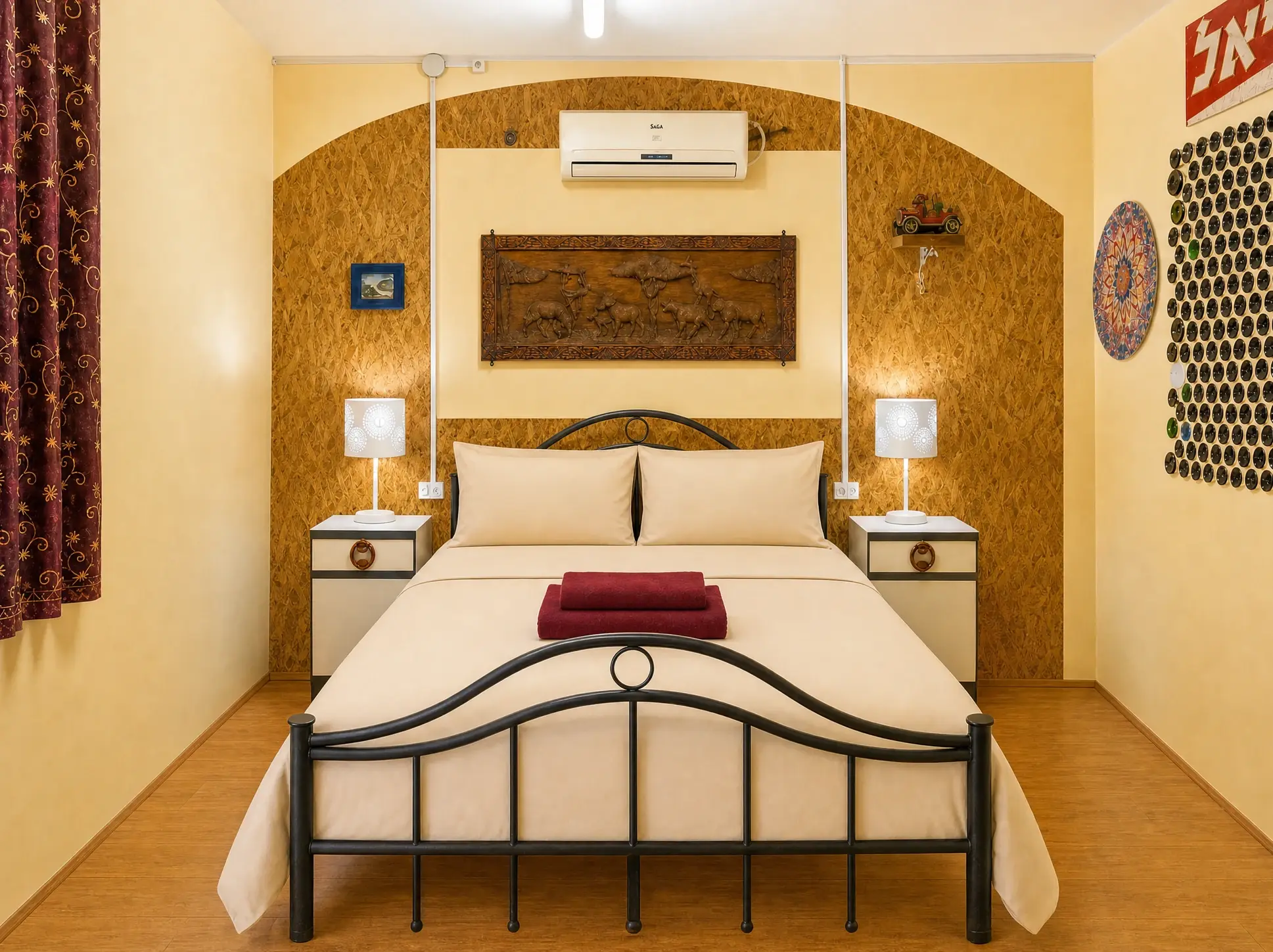 The Vintage room: a double bed in a wooden arch, a carved wooden panel, bedside lamps on both sides and string lights