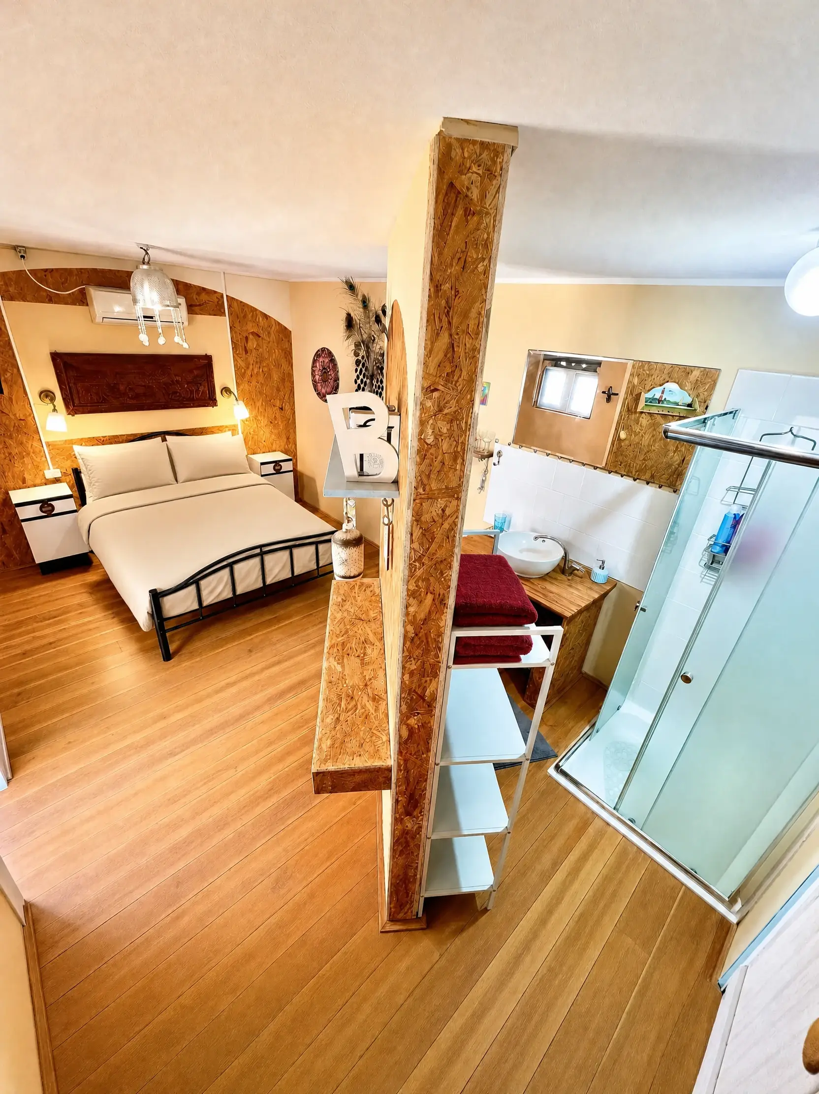 The Vintage room from another angle: a wooden post, the double bed and a glass shower