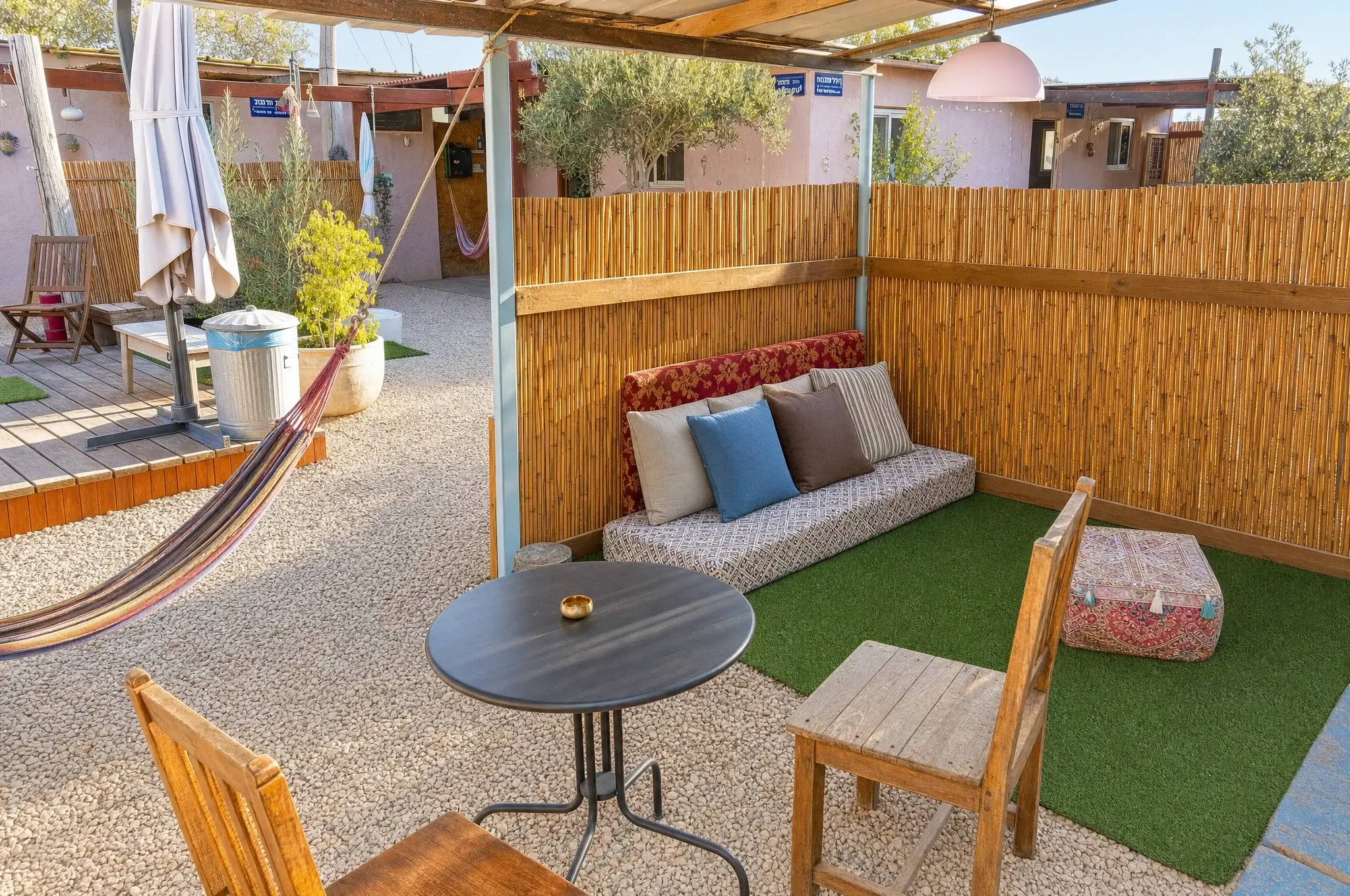A sitting corner outside: cushions, a bamboo fence and a round table