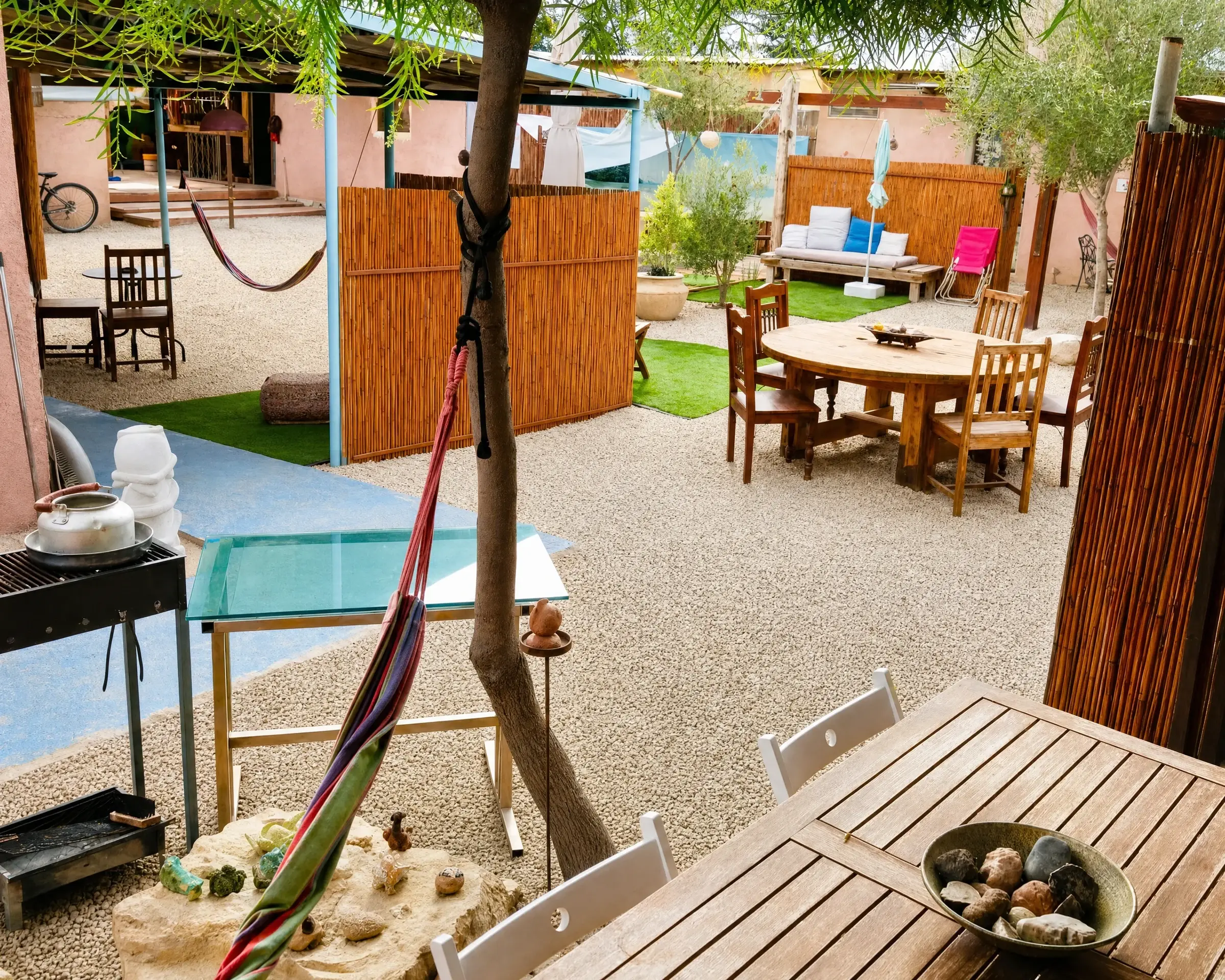 A sitting area in the yard with a hammock and wooden tables